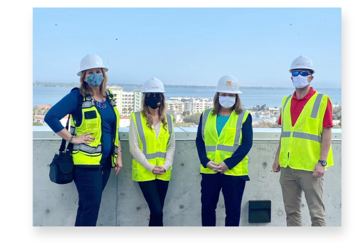 Four Chamber members standing on top of a building wearing construction safety equipment