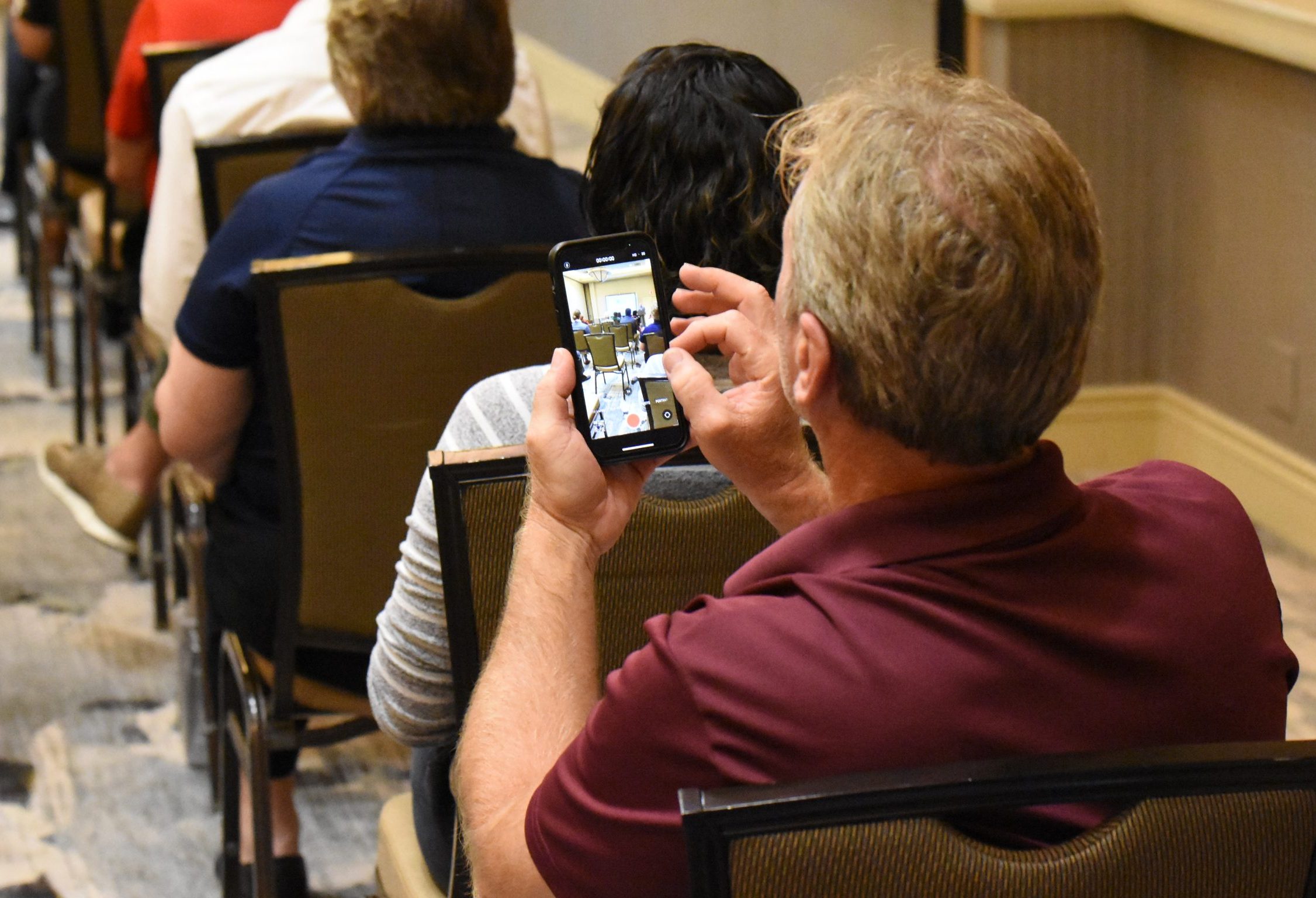 Man taking a photo on his phone during a Melbourne Regional Chamber council meeting