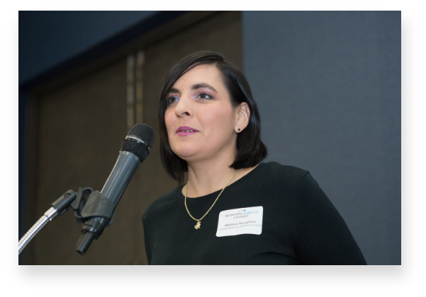 Woman speaking into microphone at a Women of Excellence event